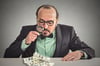 Businessman looking at cash with a magnifying glass