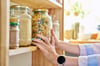 Woman taking jar of dried pasta off shelf