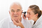 Doctor using scope to look inside man's ear.