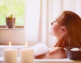 A young woman relaxes in the bath tub with candles