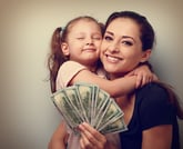 Smiling mother and happy daughter with dollars.