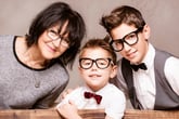 Woman, two boys wearing eyeglasses.