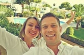 A couple takes a selfie from their hotel room balcony