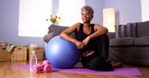 woman sitting on floor by exercise ball.
