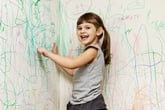Girl drawing on wall with crayon