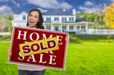 Woman with Home for Sale/Sold sign.