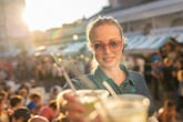 Woman at crowded venue reaching for cold drink.