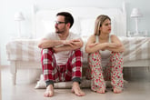 Couple in pajamas facing opposite directions.