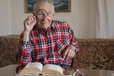 Older man looking through magnifying glass at camera