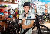 Young man holding bike in bike shop.