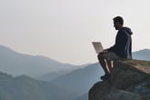 Man with laptop on mountaintop