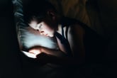 Boy on cellphone in bed.
