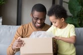 A father and his child open a box from an online purchase