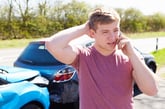 Young man on phone after car accident