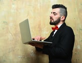 Young hip white businessman beard, stylish haircut holding laptop