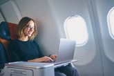 Woman flying in an airplane and using a laptop
