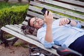Man with cellphone on park bench