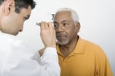 A doctor examines the eyes of an older patient