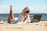 Woman looking at computer on beach