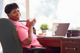 A black woman works from home over a cup of coffee