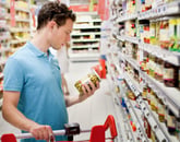 A man holds a jar of olives at the grocery store