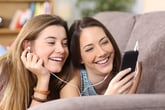 Two young women stream a show on a phone
