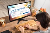 A young woman at her desktop computer searching for the best insurance companies for her car