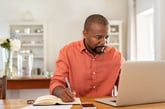 A man plans his finances on his laptop and with notes