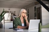 Older woman working on laptop and stressed