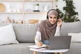 Happy woman studying online with laptop and headphones taking online class