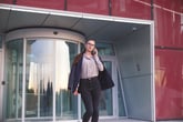 Businesswoman walking out of building on her phone