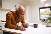 Retiree reviewing financial documents in his kitchen