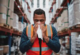 A sick warehouse worker blowing his nose