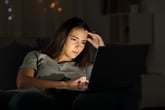 Stressed woman searching for jobs online at night with laptop