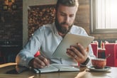 Bearded man studying investing basics on his tablet