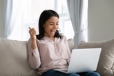 Excited woman gestures thumbs-up while using a laptop