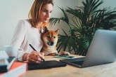 Graphic artist woman working at home with her dog on laptop