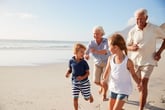 Retired senior couple running on the beach with grandkids