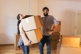 Man and woman couple carrying boxes preparing to move into new home