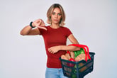 Woman with a basket of groceries giving thumbs down