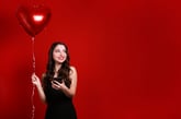 Woman with cell phone and a heart balloon