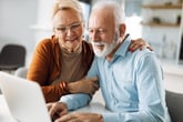 Happy senior couple using computer at home