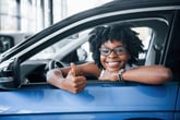 Woman driving car and giving thumbs up