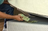 Man hiding cash under a mattress
