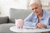 Senior woman counting money in front of piggy bank