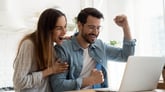 Excited millennial couple celebrating their online purchase at laptop
