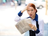 Shocked woman reading a newspaper.
