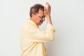 Upset older man slapping his forehead in regret
