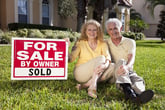 Older couple in front of their home they sold to downsize