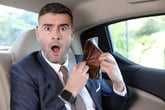 Shocked man in a suit with an empty wallet